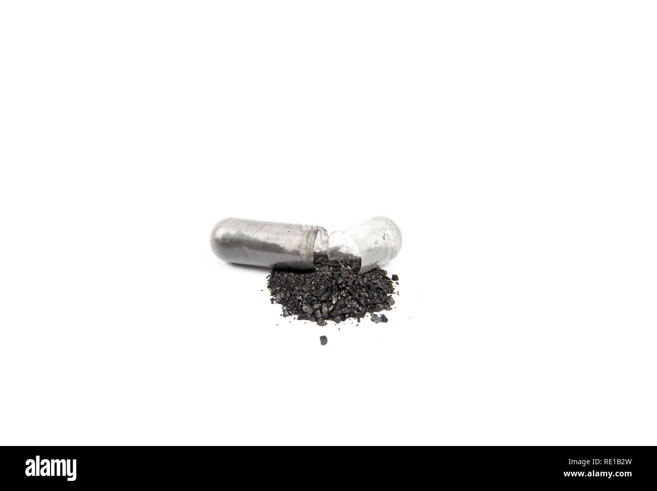 Opened activated charcoal capsule also known as activated carbon as medical drug isolated on white. Stock Photo