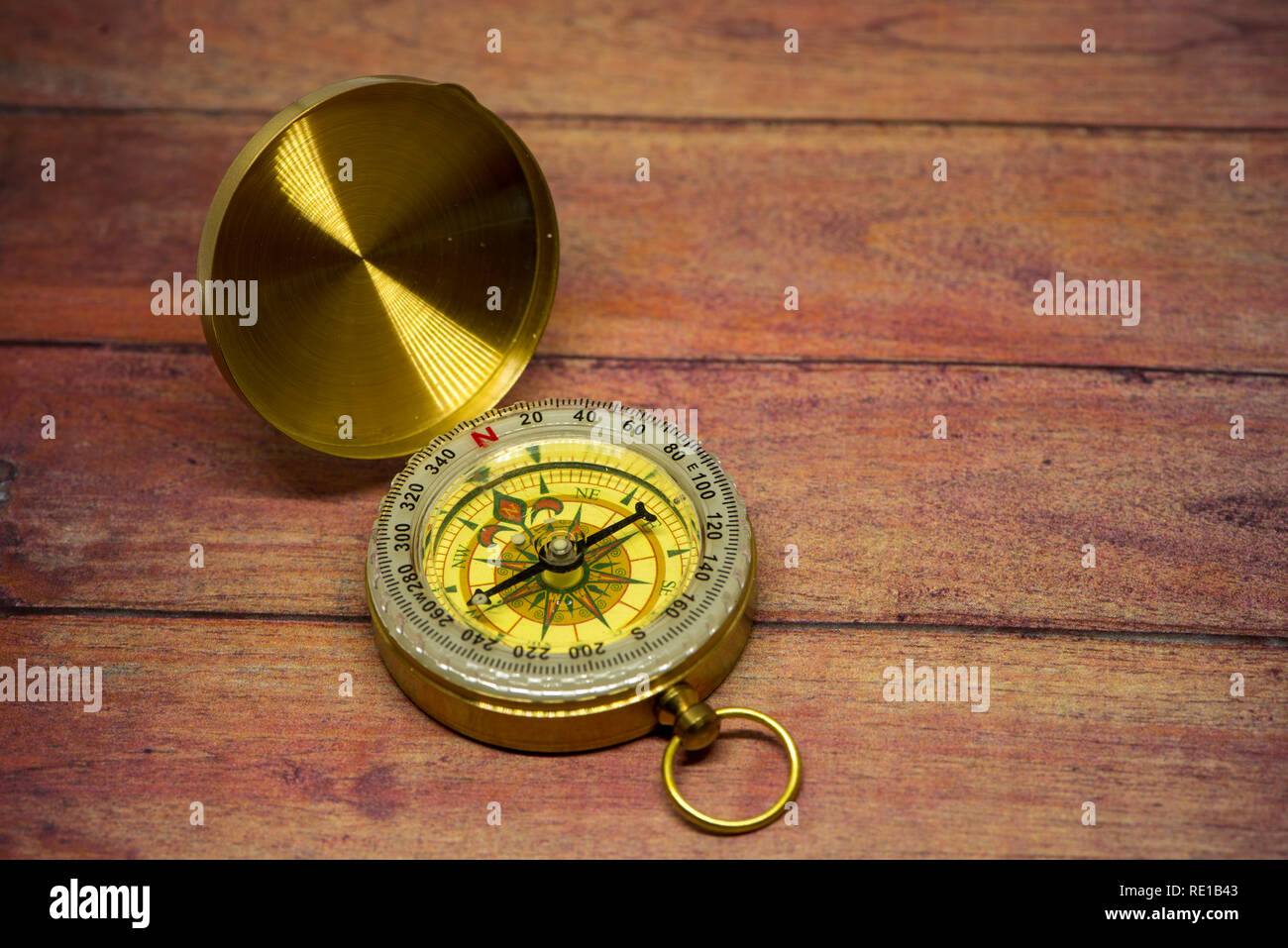 An old compass on a brown wooden table Stock Photo