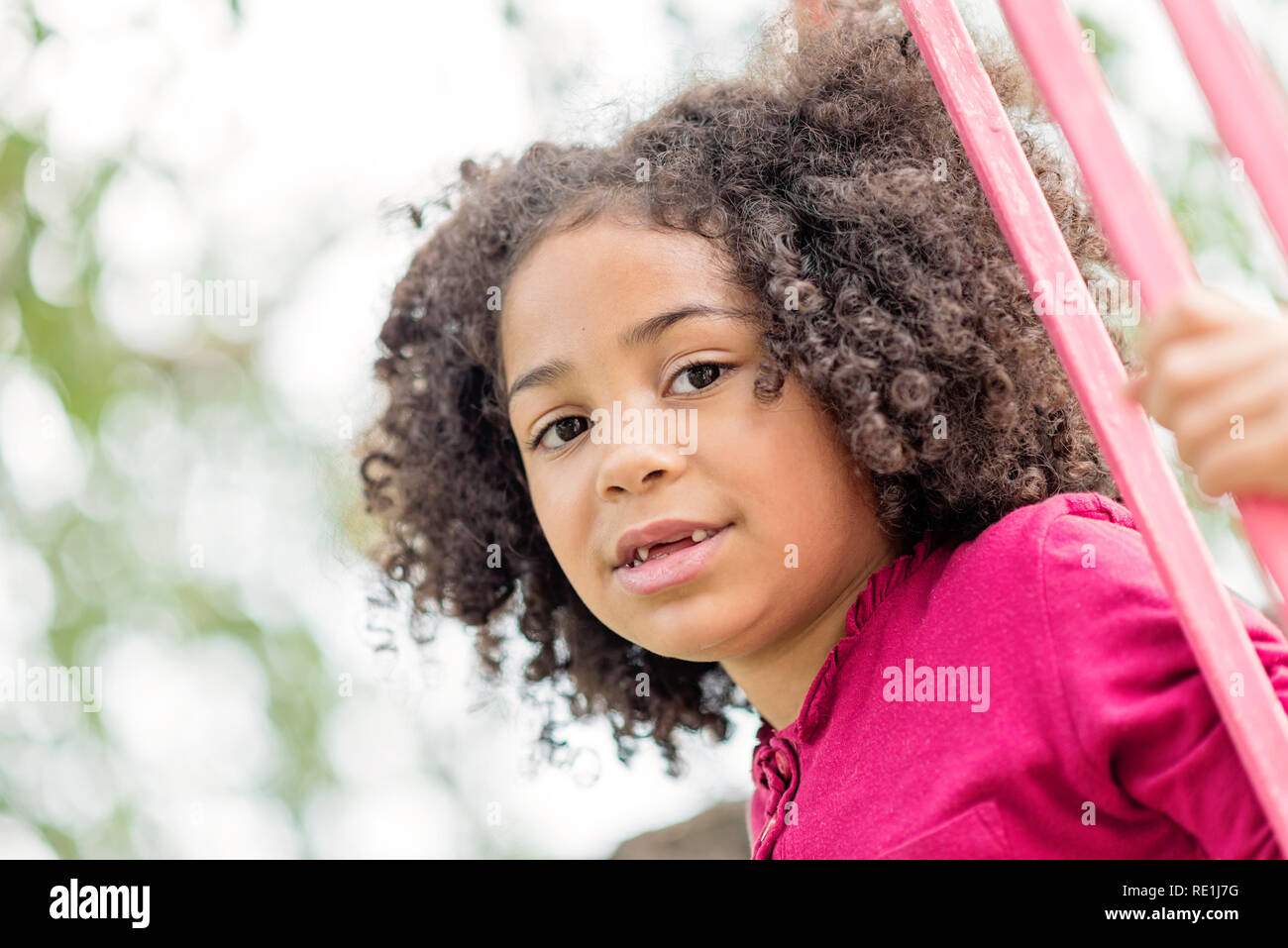 Smiling cute little african american girl with curly hair looking at ...