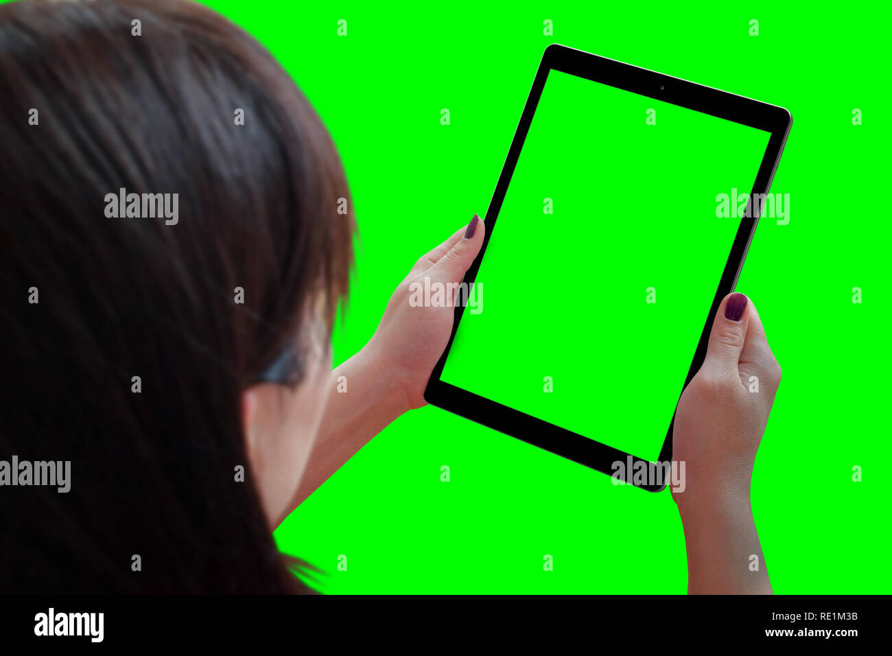 Woman play game or watching video on tablet. Isolated background and screen in green. View over the shoulder. Stock Photo