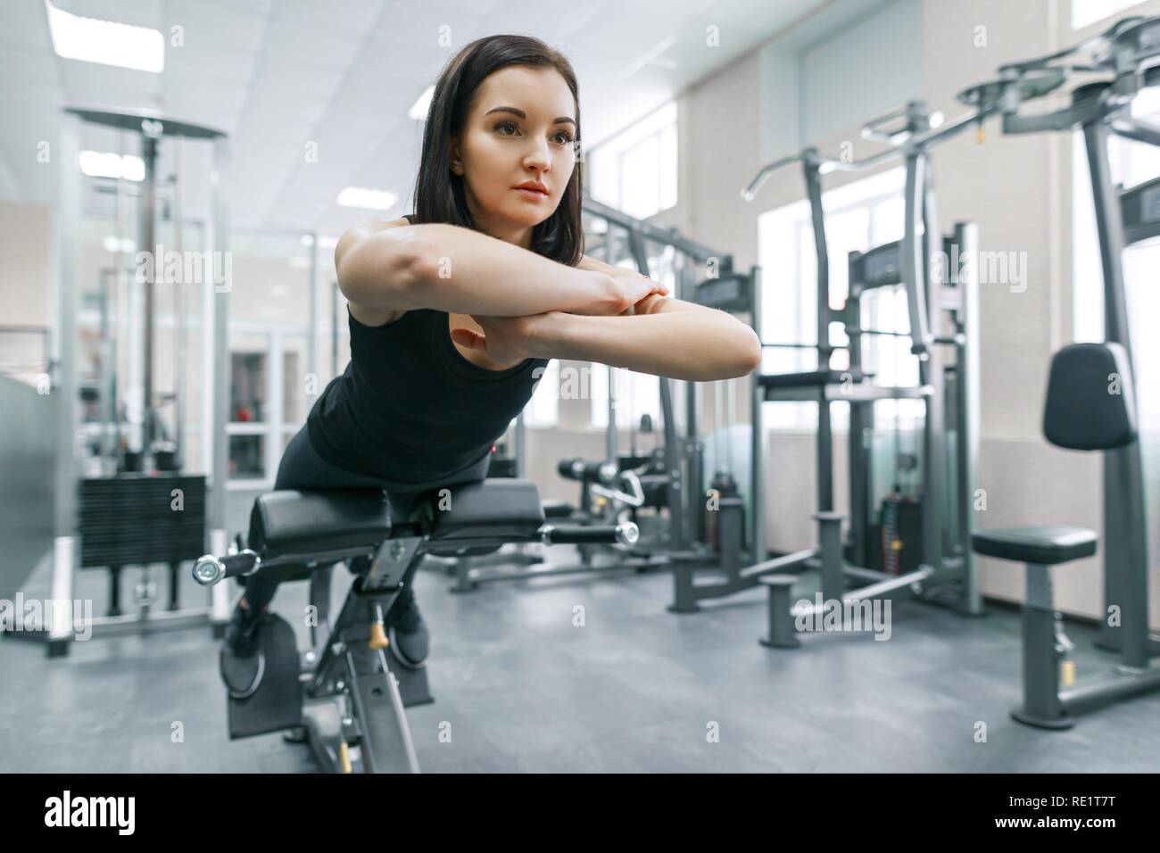 Young athletic woman exercising on the machines in modern sport gym