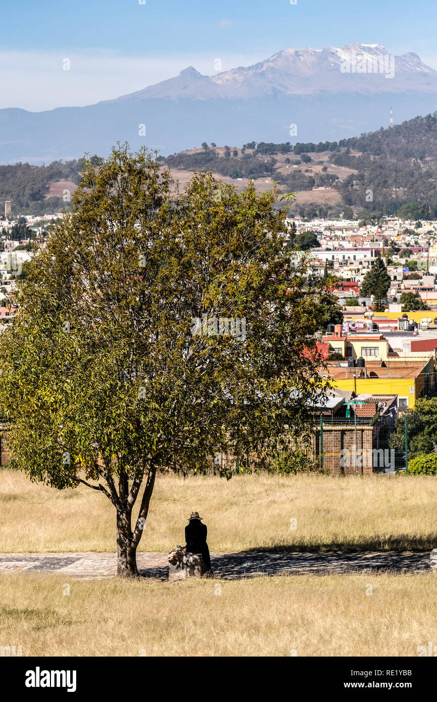 A lone female figure sitting under a tree at Puebla, Mexico Stock Photo