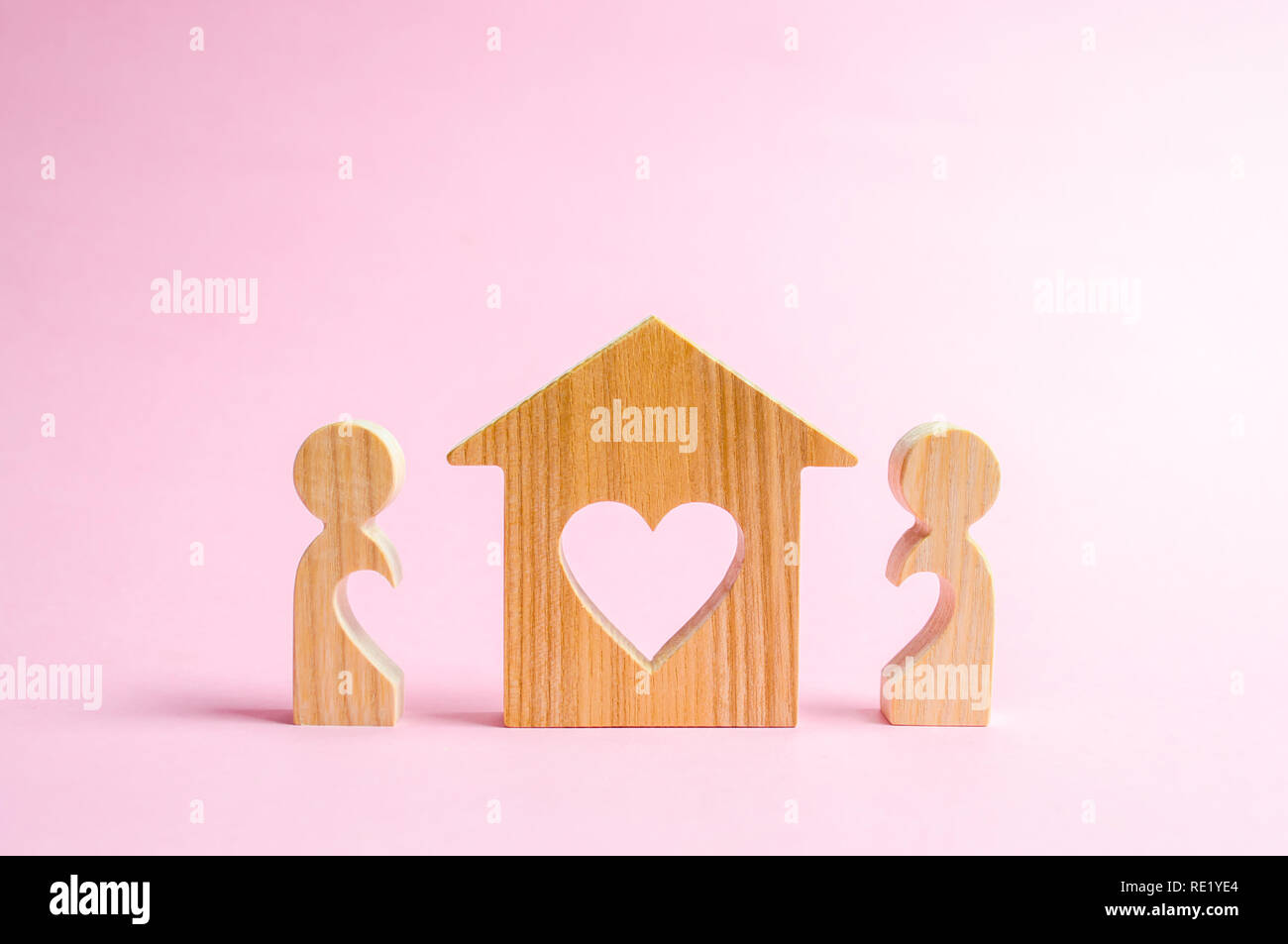 A house with a heart stands between a pair of lovers. The concept of