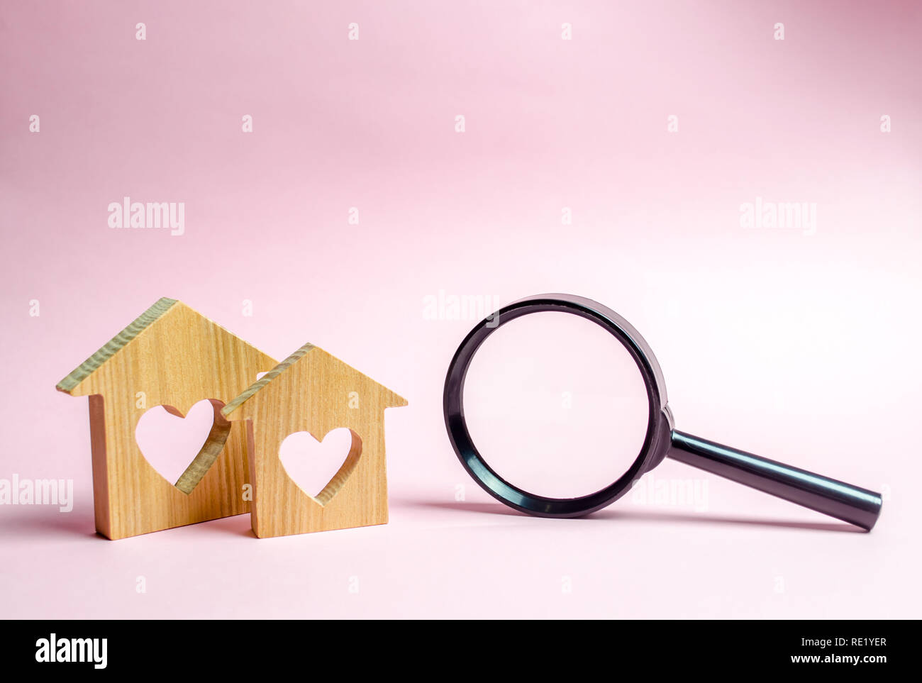 Two wooden house with a heart and a magnifying glass. The concept of
