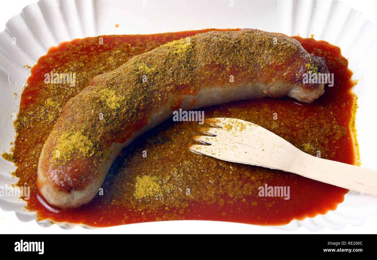 Currywurst with curry sauce on a paper plate, hot pork sausage Stock Photo