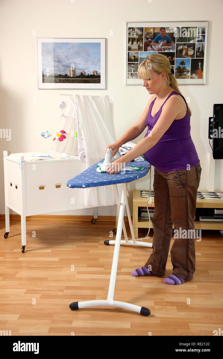 Pregnant woman, 9th month, at home, doing light housework, ironing