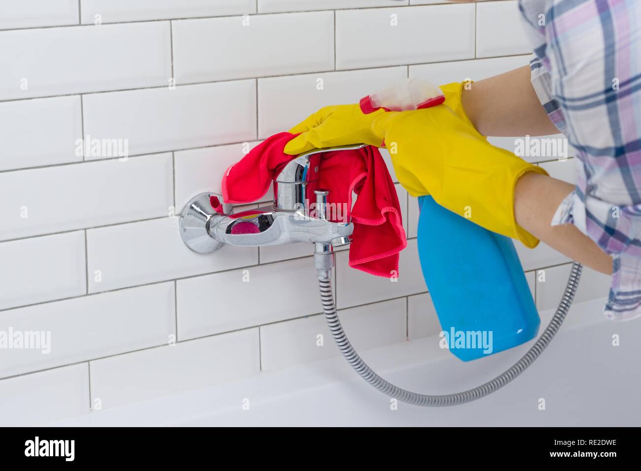 Housework and domestic lifestyle. Woman doing chores in bathroom at home, cleaning wash basin and tap with spray detergent. Stock Photo