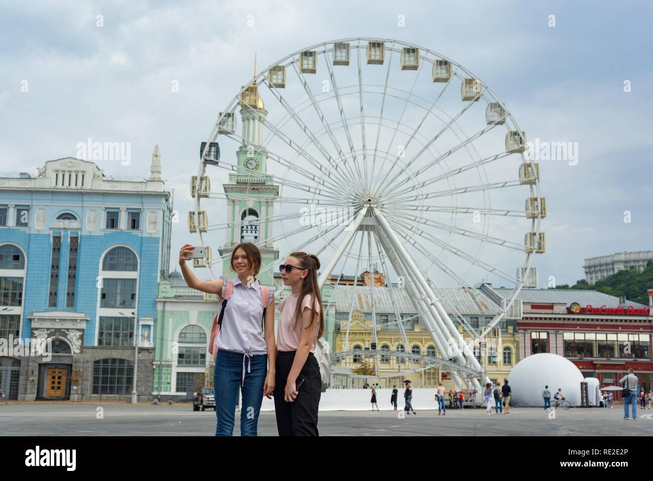European city, entertainment ferris wheel on the square. Young girls tourists are photographed in the background of the Ferris wh Stock Photo