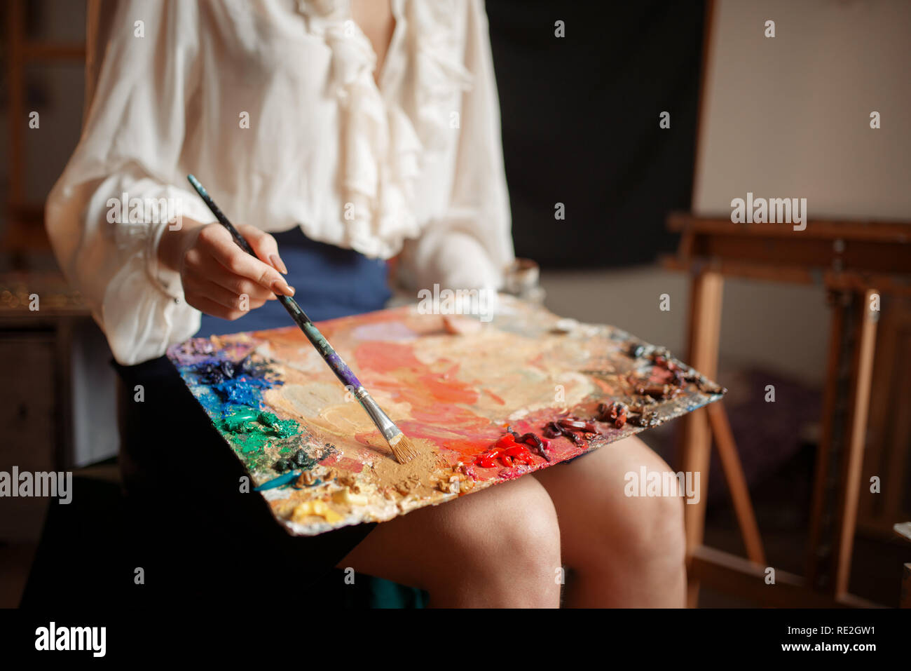 Female painter holds color palette and brush in studio. Creative ...