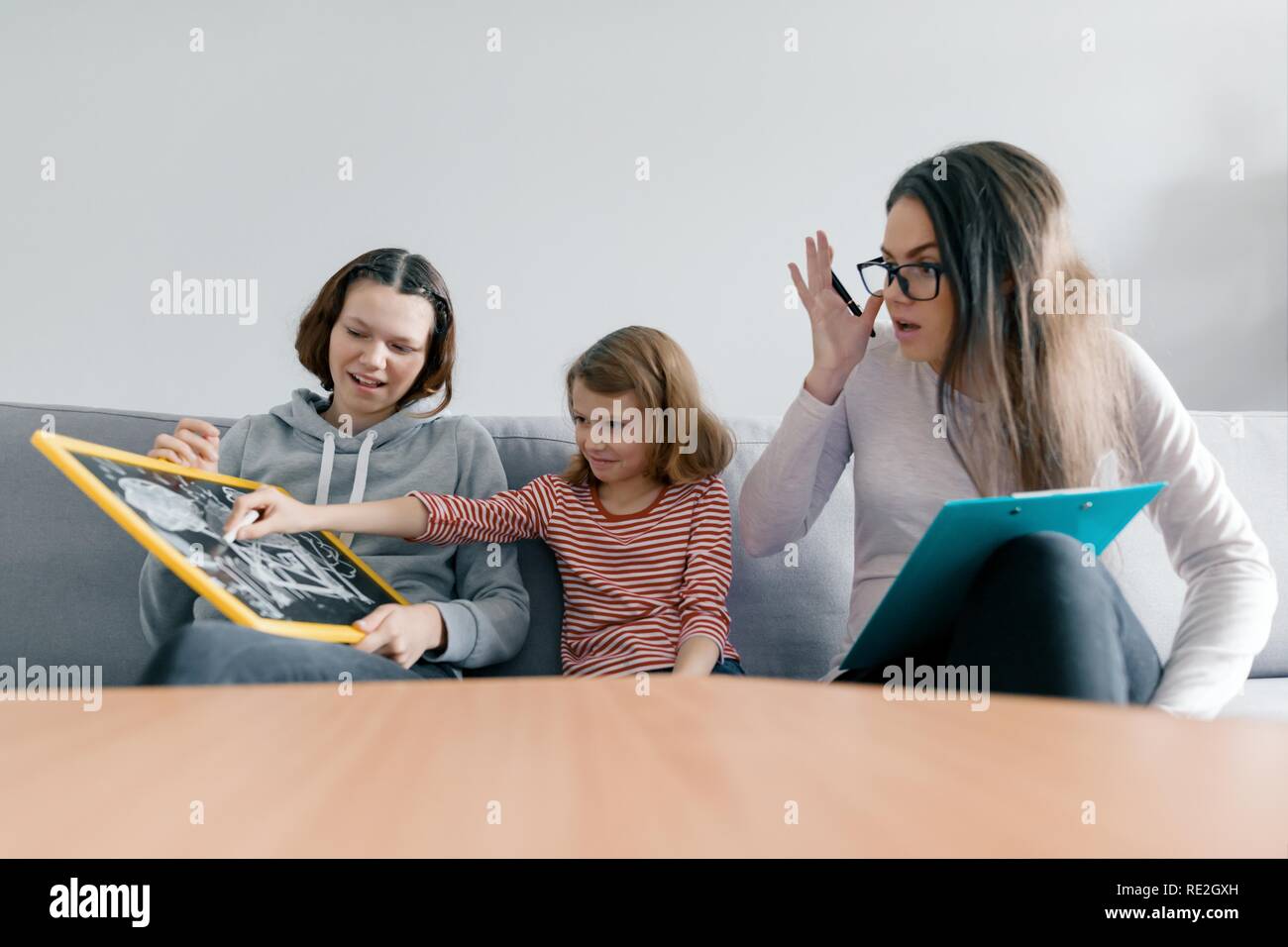 Two sister girls talking with young woman family psychologist, children sitting in office. Stock Photo