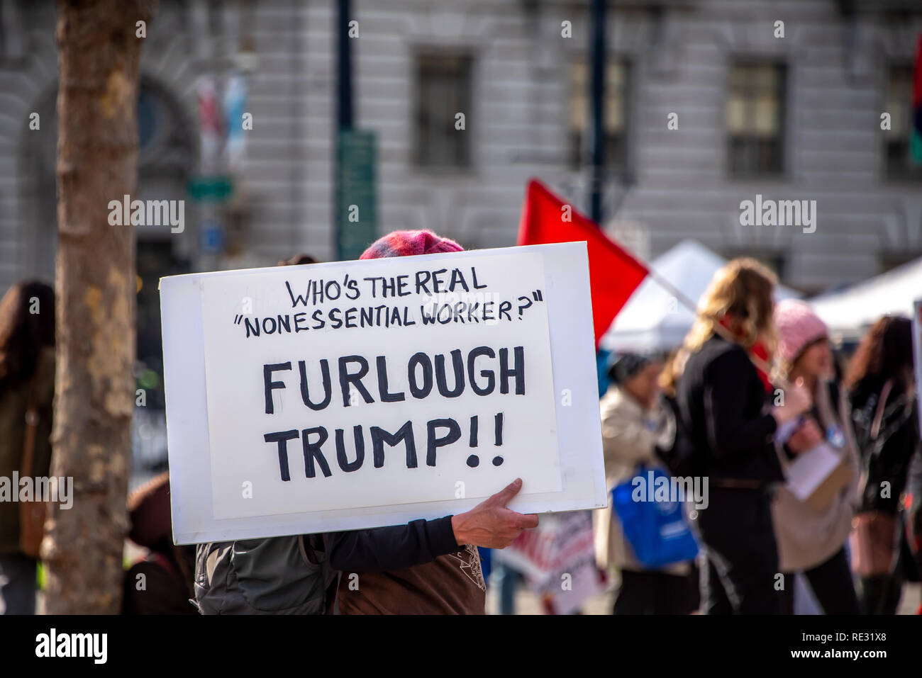San Francisco, USA. 19th January, 2019. The Women's March San Francisco begins with a rally at Civic Center Plaza in front of City Hall. A protester carries a sign through the plaza questioning, 'Who's the real 'nonessential worker'? Furlough Trump!' Credit: Shelly Rivoli/Alamy Live News Stock Photo