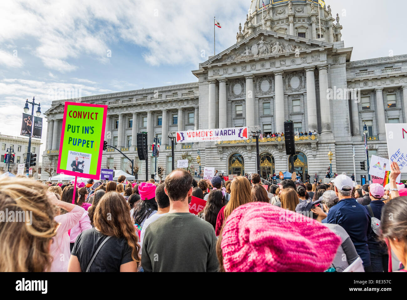 San Francisco, USA. 19th Jan 2019.  Participants to the Women's March event hold signs with various messages; the rally stage and the City Hall building visible in the background Stock Photo