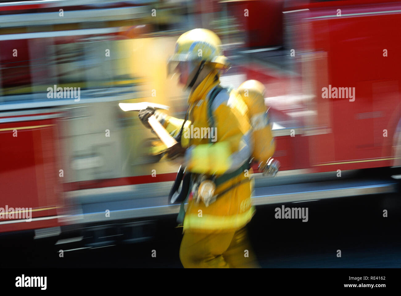 A fireman in full turnouts is carrying an axe at a fire site, USA Stock Photo