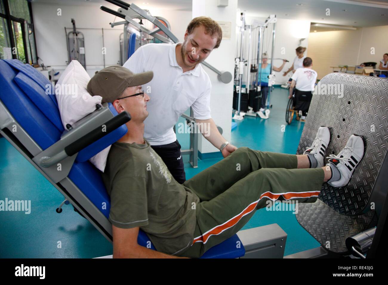 Patients during muscle strength training on various machines in a gym, physiotherapy, physical therapy in a neurological Stock Photo
