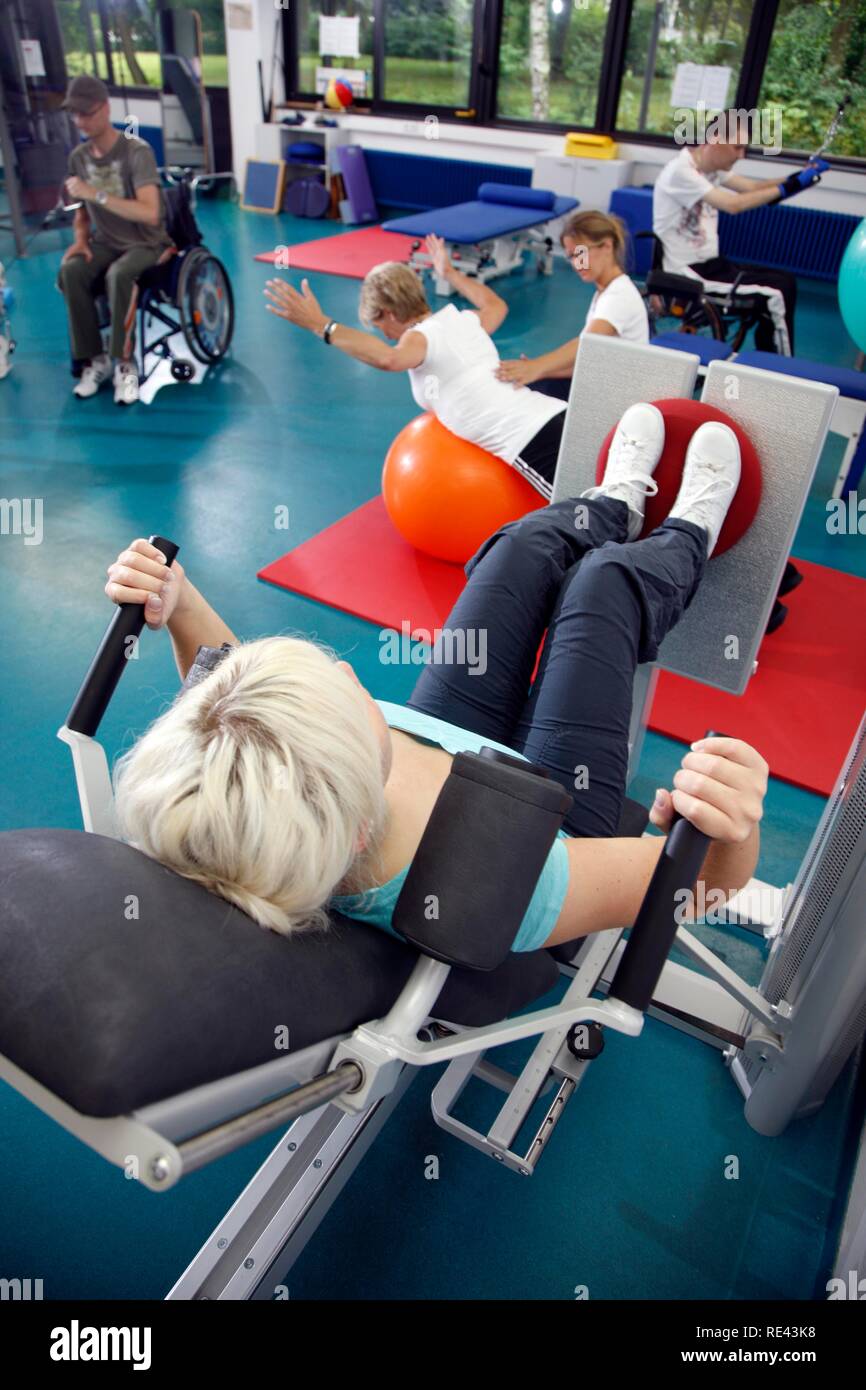 Patients during muscle strength training on various machines in a gym, physiotherapy, physical therapy in a neurological Stock Photo