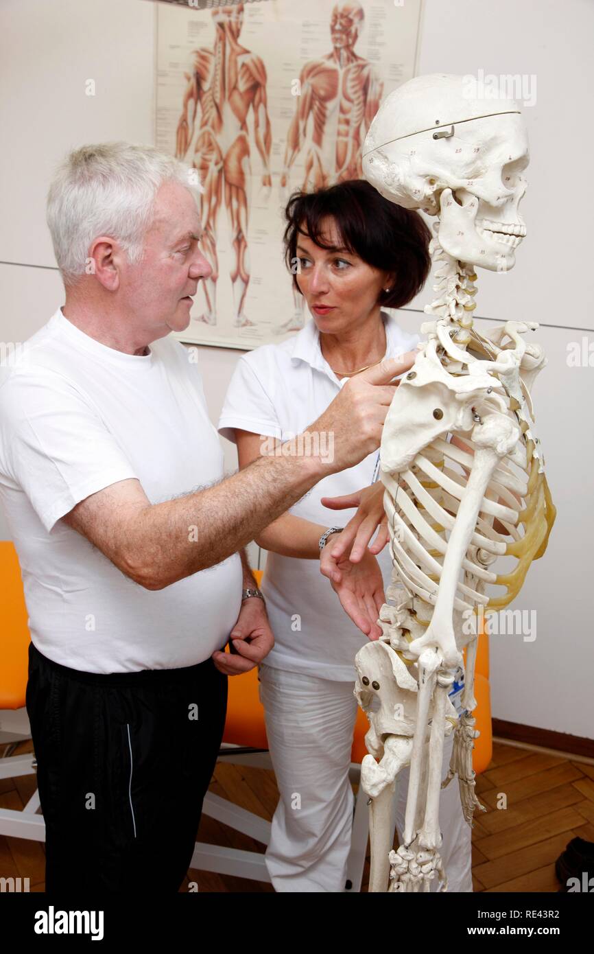 Therapist explaining to a patient on the basis of a skeleton the anatomical basis for a physiotherapy treatment, physical Stock Photo