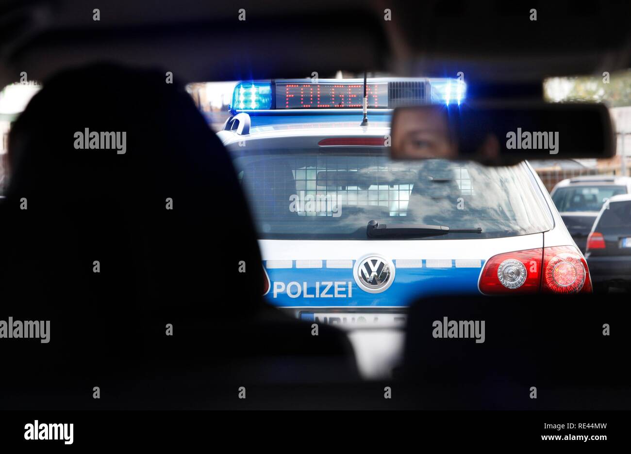 A police patrol car with flashing lights and fluorescent letters 'Folgen' follow, has stopped a vehicle, traffic control Stock Photo