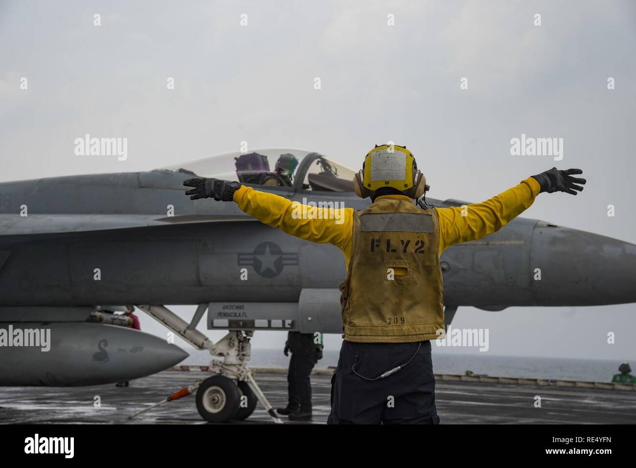 ARABIAN GULF (Nov. 24, 2016) Petty Officer 3rd Class Kenneth Tenoso signals to Capt. Jeffrey Anderson, Commander, Carrier Air Wing Three inside the cockpit of an F/A-18E Super Hornet assigned to the Sidewinders of Strike Fighter Squadron (VFA) 86 on the flight deck of the aircraft carrier USS Dwight D. Eisenhower (CVN 69) (Ike). Ike and its Carrier Strike Group are deployed in support of Operation Inherent Resolve, maritime security operations and theater security cooperation efforts in the U.S. 5th Fleet area of operations. Stock Photo