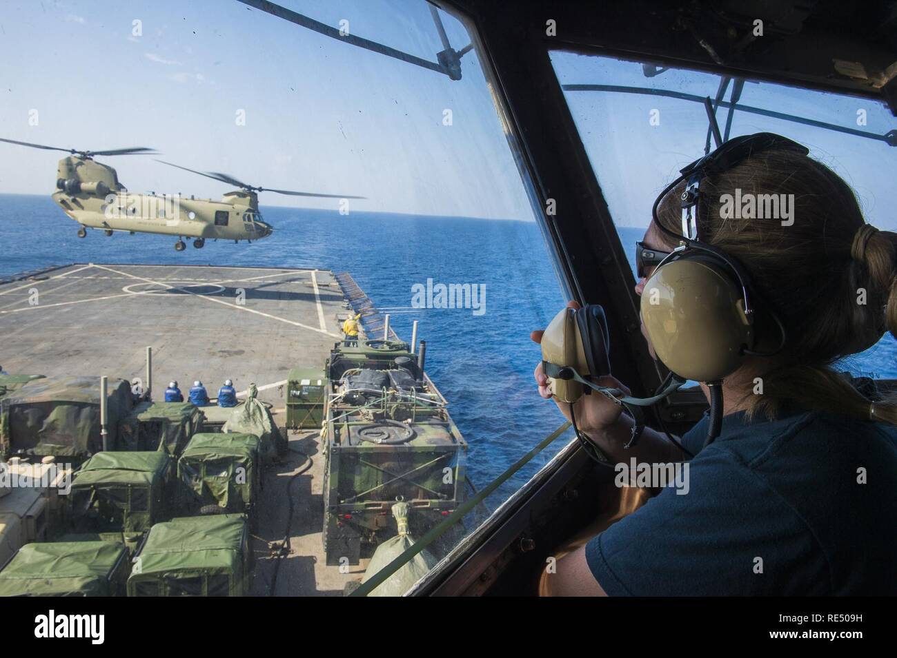 A United States Navy sailor talks to pilots from the tower as they land a CH-47 Chinook from the United States Army 82d Combat Avaition Brigade onto the USS Whidbey Island (LSD 14) in the Gulf of Aden, Nov. 11, 2016. The training allowed troopers from the 82d CAB to get their qualification in landing on naval ships, each crew member had to perform five day-time landings and five night-time landings using NVG capabilities. The 82d CAB rapidly deploys in support of the Global Response Force to conduct decisive aviation operations worldwide. Enabling the ground force commander with air assault, a Stock Photo