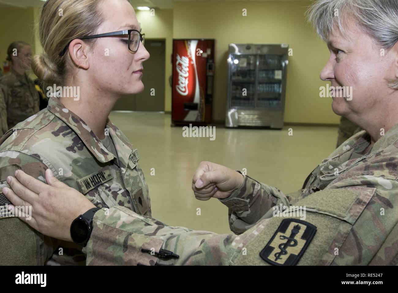 U.S. Army Spc. Jenna Van Horn, a newly promoted pharmacy specialist, is pinned by her mother, U.S. Army Maj. Lisa Van Horn, the chief of patient administration, both assigned to the 452nd Combat Support Hospital during Jenna Van Horn's promotion ceremony in Camp Arifjan, Kuwait, Jan. 2, 2019. The Van Horns shared the unique experience of deploying together as a mother and daughter team to help support the health readiness of service members throughout Central Command's area of responsibility. Stock Photo