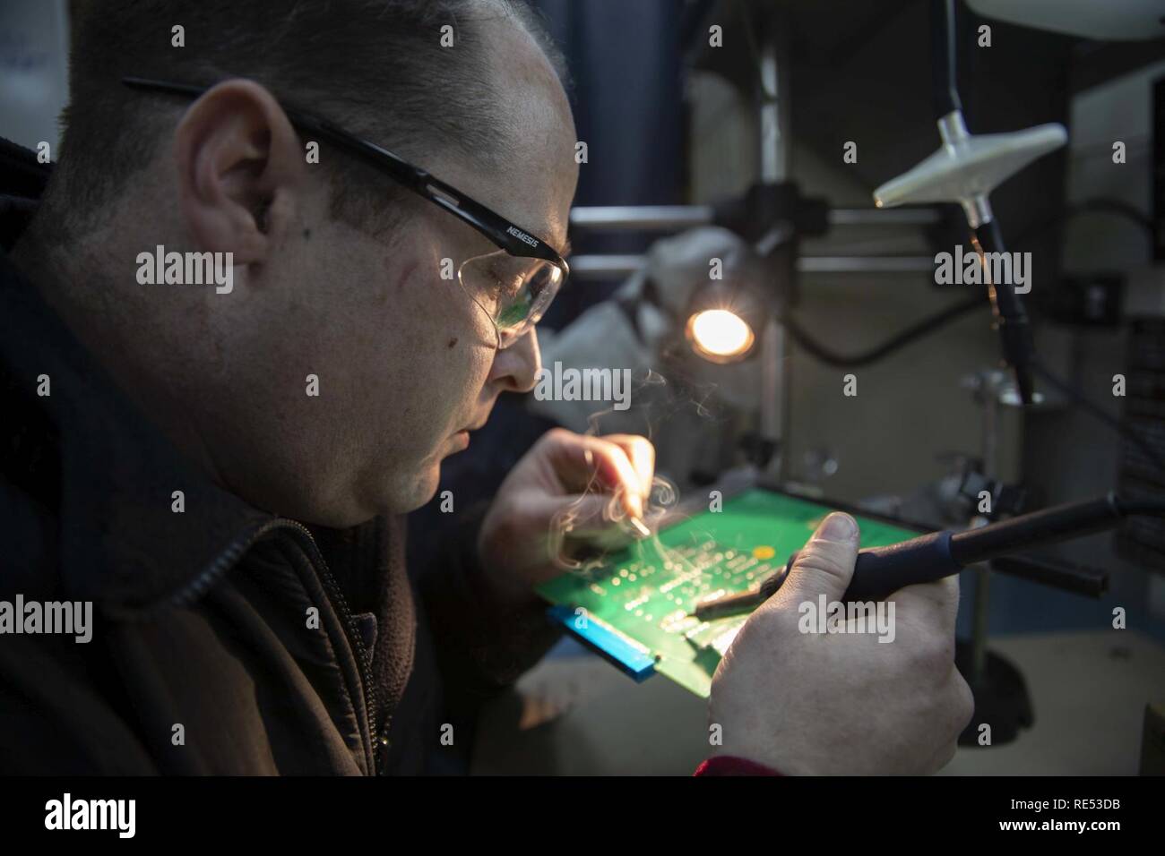 MEDITERRANEAN SEA (Jan. 5, 2019) Aviation Electronics Technician 1st Class Christopher Monger installs a new micro circuit on a circuit card for a CH-53E Super Stallion in the aviation intermediate maintenance department solder shop aboard the Wasp-class amphibious assault ship USS Kearsarge (LHD 3). Kearsarge is on a scheduled deployment as part of the Kearsarge Amphibious Ready Group in support of maritime security operations, crisis response and theater security cooperation, while also providing a forward naval presence. Stock Photo