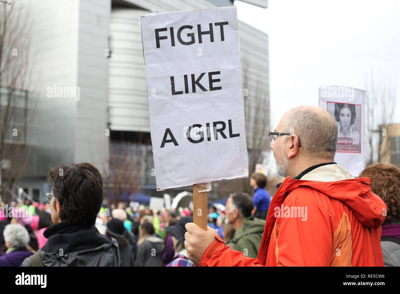 A man holding a sign that reads "fight like a girl" at the Women's