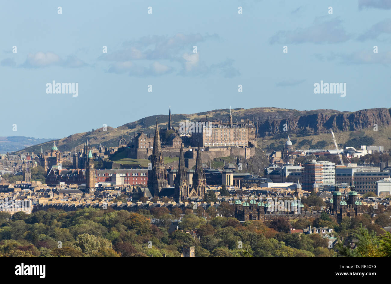 A cityscape photograph of the City of Edinburgh, Scotland, showcasing Edinburgh Castle and the Salisbury Crags on a clear day in Autumn. Stock Photo