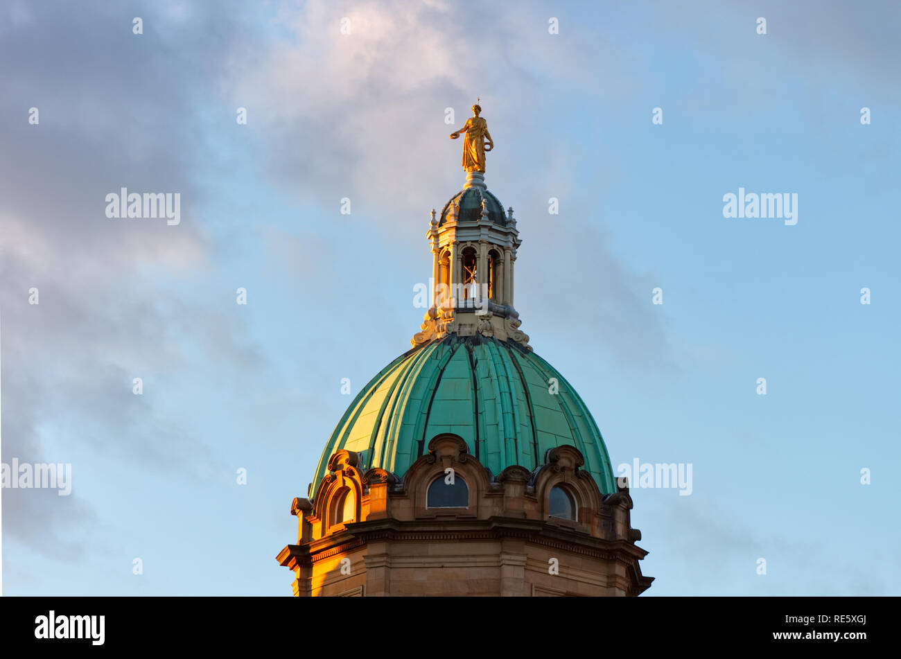 A statue of an angel sitting at the top of the dome of the Mound Museum in Edinburgh, Scotland, UK at sunset. Stock Photo