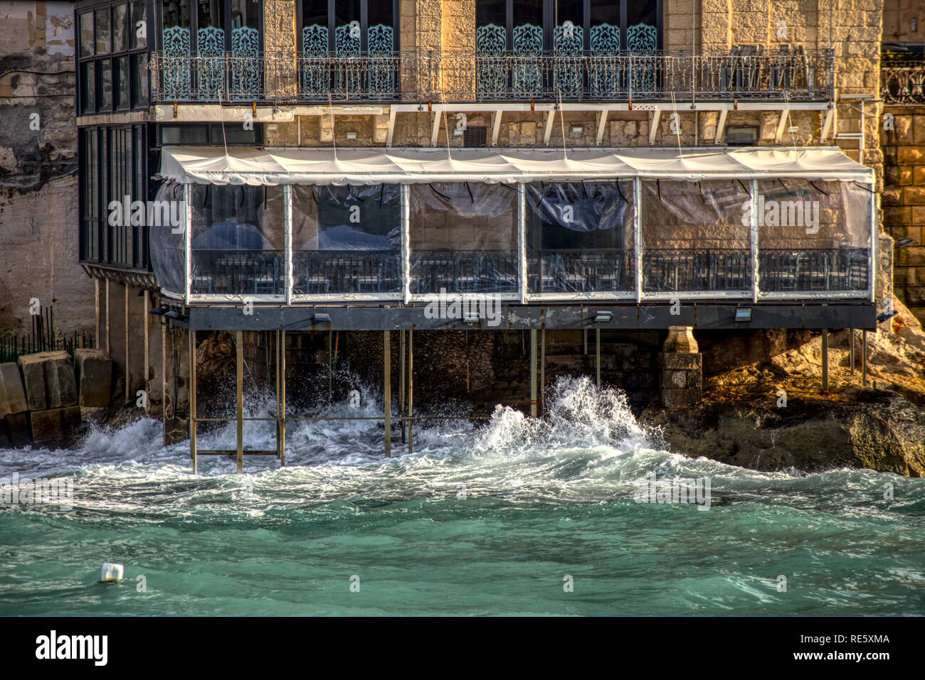 A restaurant on the island of Malta supported by pillars over the sea is being battered by the waves Stock Photo