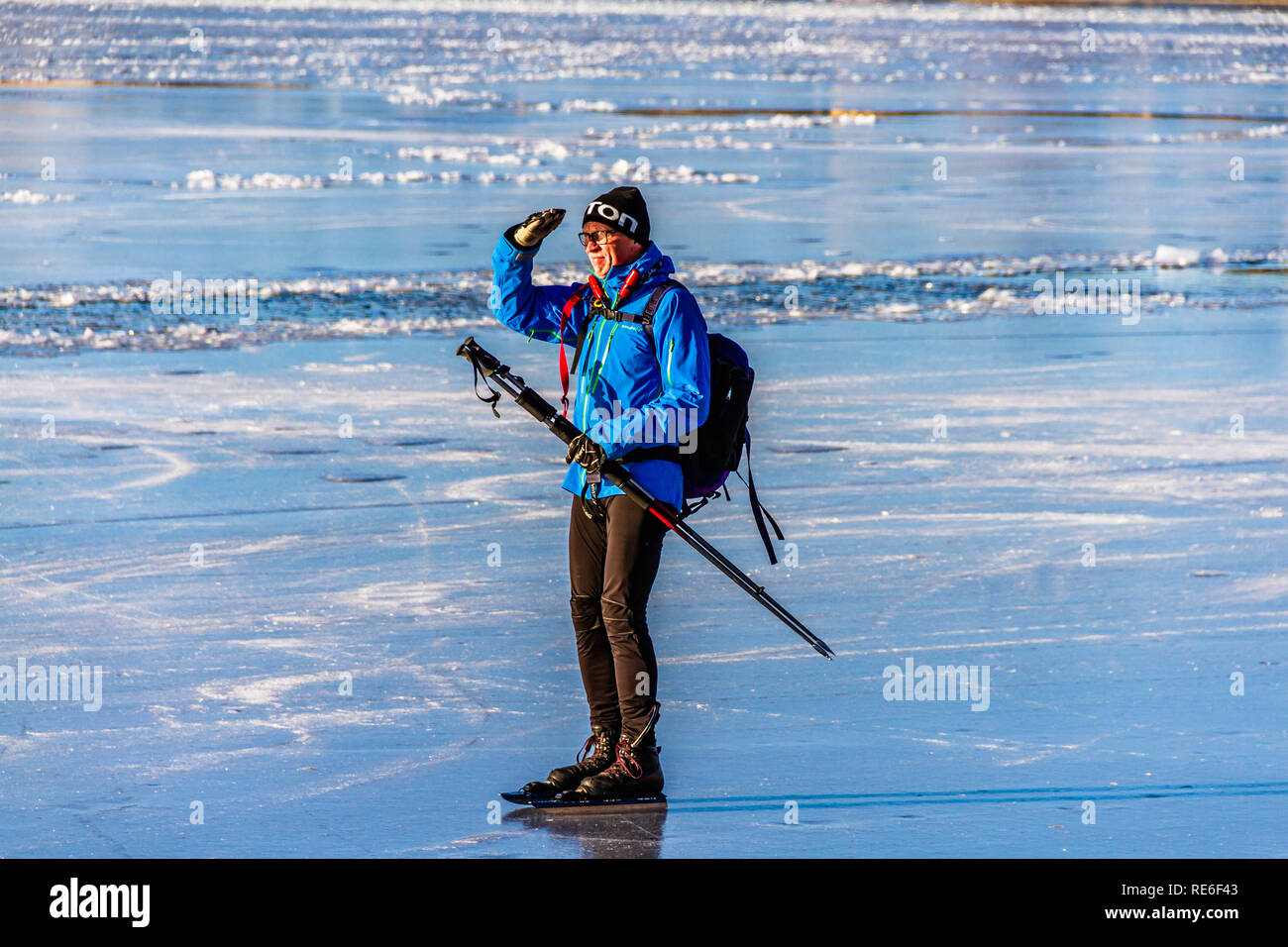 An ice skater shields their eyes from the winter sun on frozen Lake ...