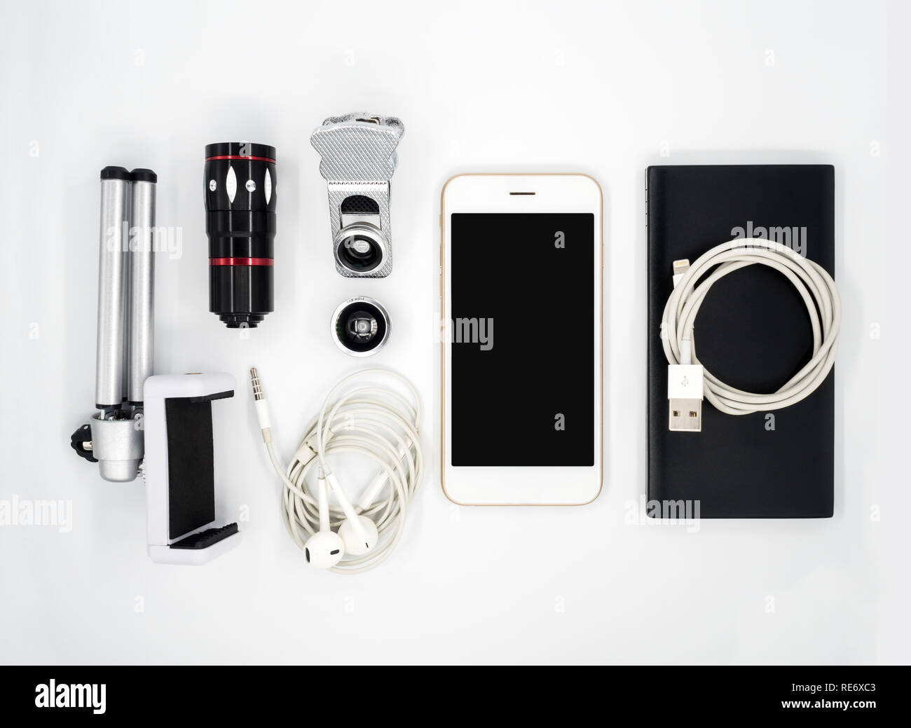 Flat lay (Top view) image of accessories (Tripod Phone Holder, Universal Clamp Camera Lens, Earphone, Power Bank, USB Charger Cable) around smartphone Stock Photo