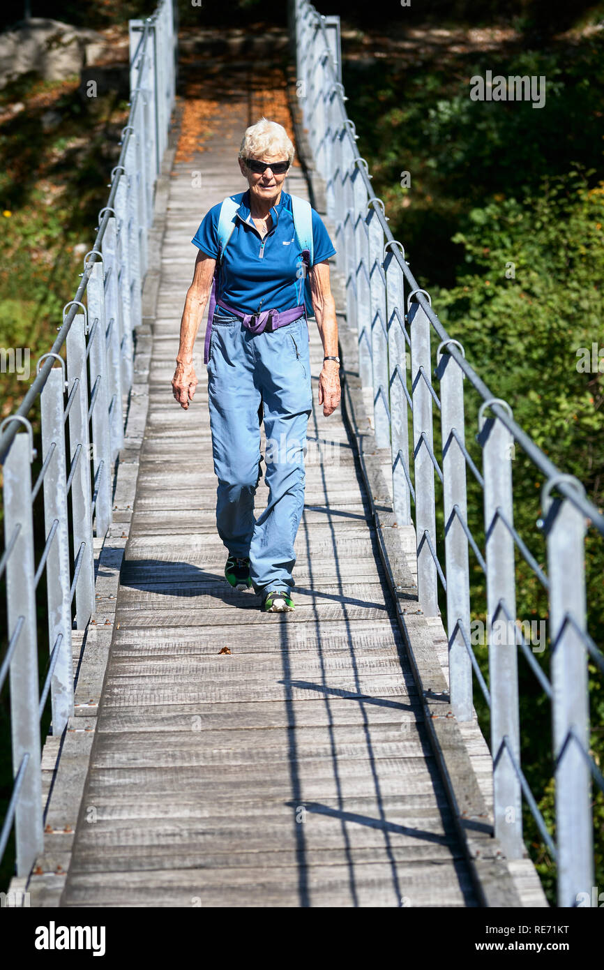 Senior citizen walking on a suspension bridge across the River Soca, near Kobarid, Primorska, Slovenia. Stock Photo