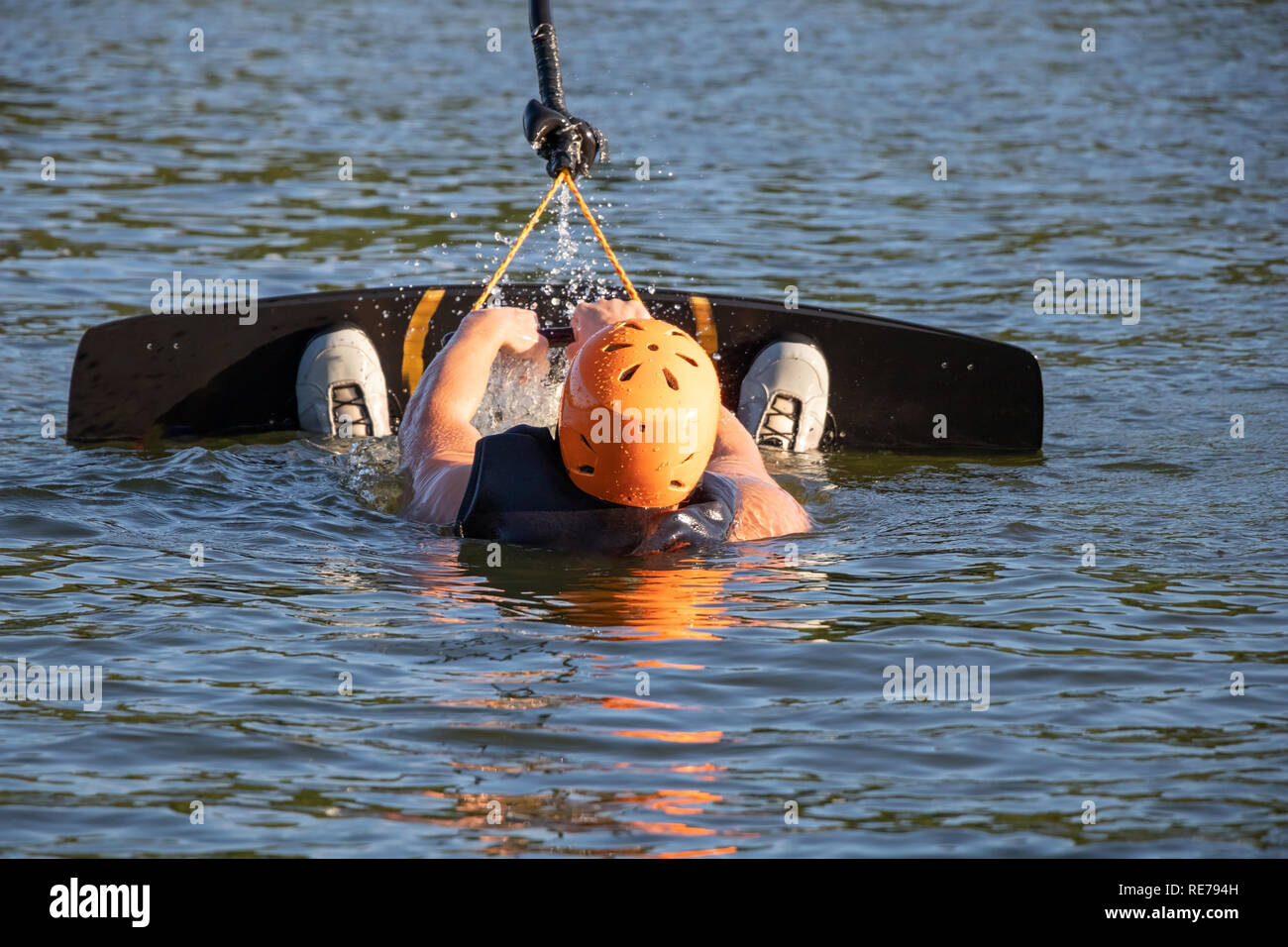 Wakeboarder holding rope and taking off from water Stock Photo