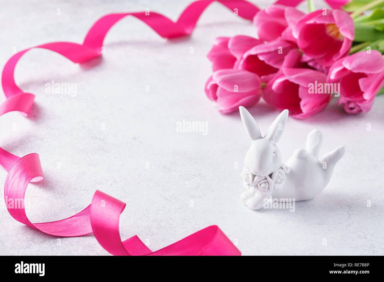 Easter background with pink tulips and cute porcelain bunny. Space for ...