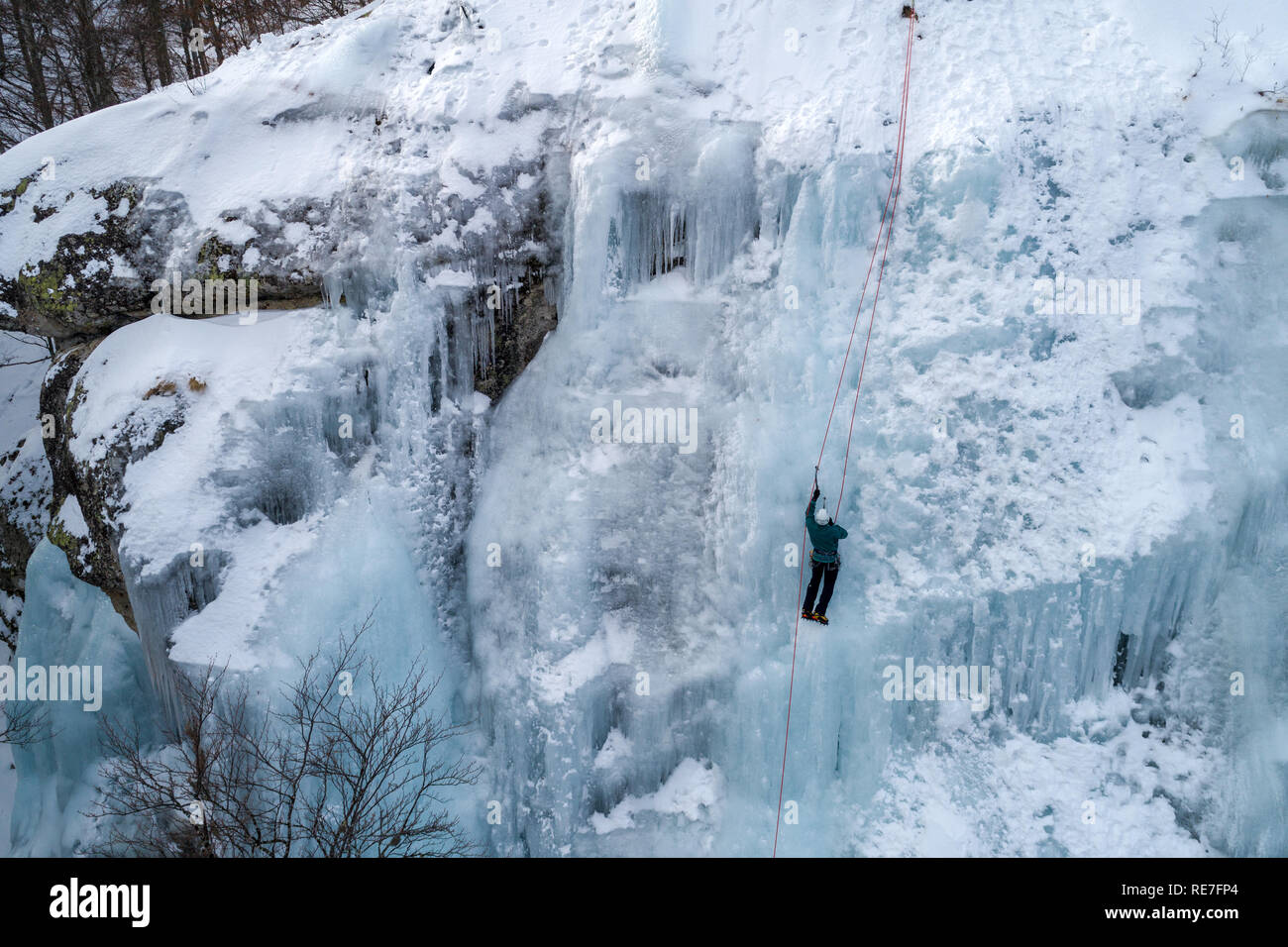 Ice climbing the North Greece, man climbing frozen waterfall. Stock Photo