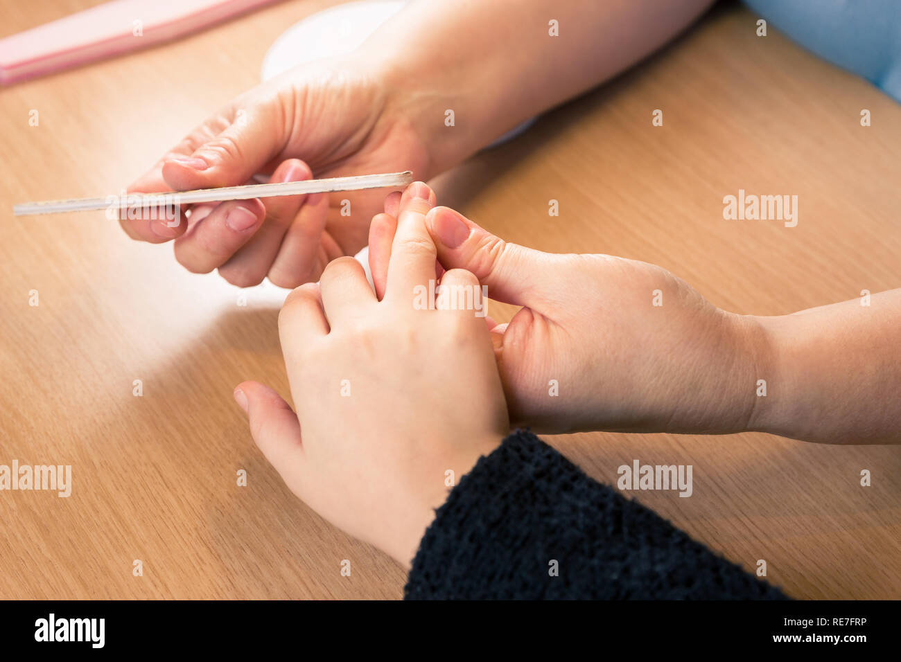 Filing nails of young girl at the kichen table, close up of the hands - horizontal Stock Photo