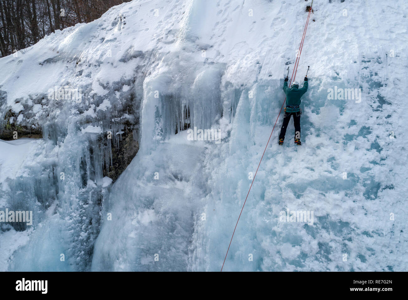 Ice climbing the North Greece, man climbing frozen waterfall. Stock Photo