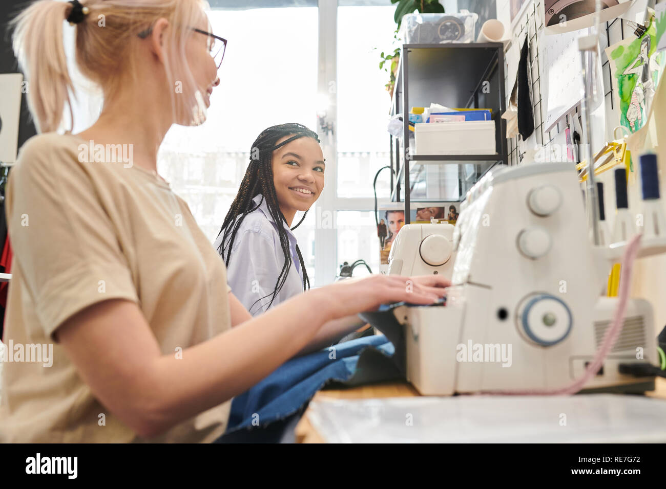 Two female tailors using sewing machines while working in design studio Stock Photo