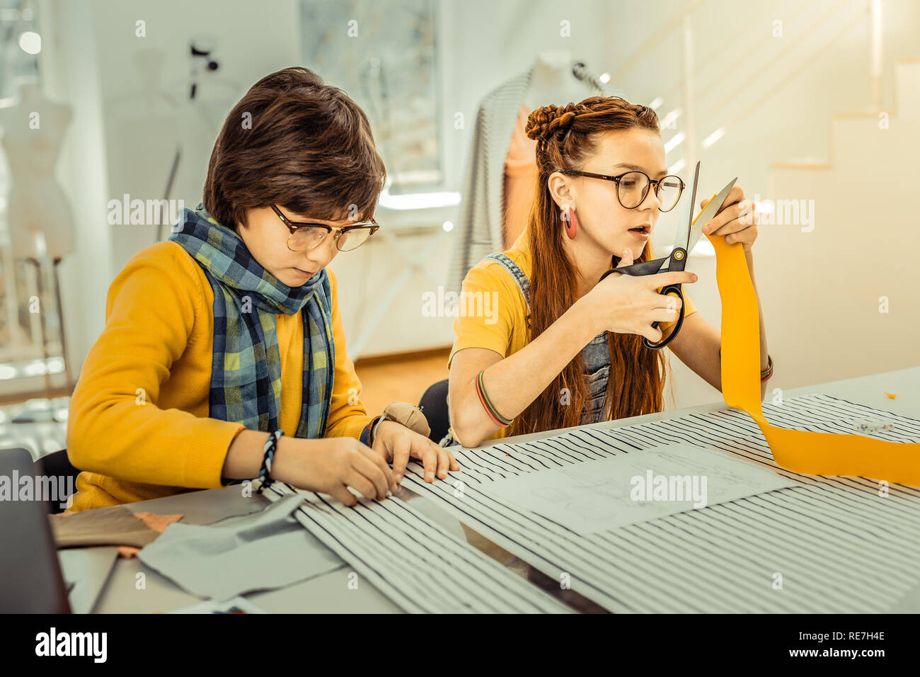 Dark-haired boy using ruler while measuring fabric Stock Photo - Alamy