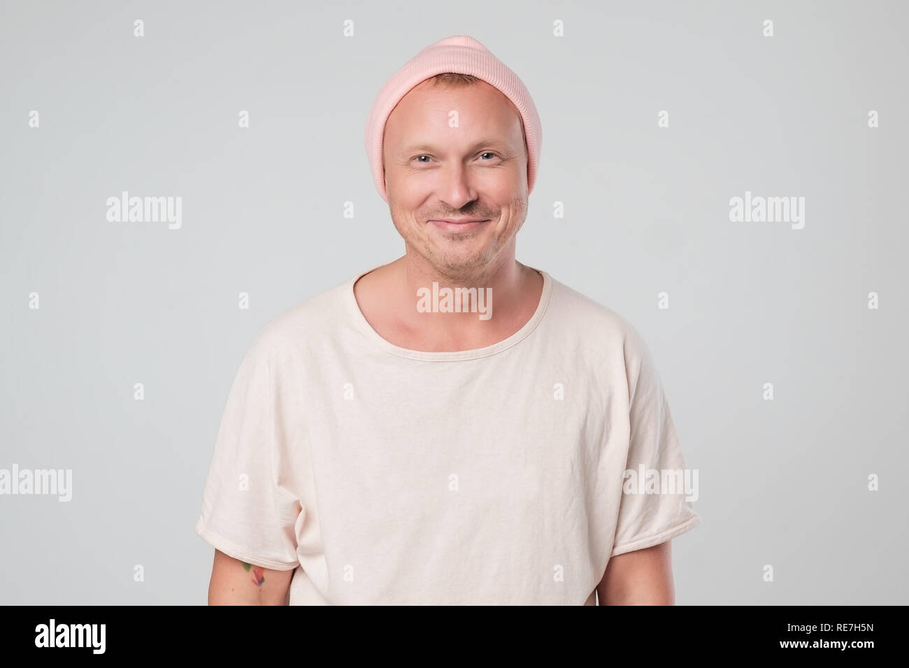 Happy young guy in pink hat looking at camera, brightfully smiling
