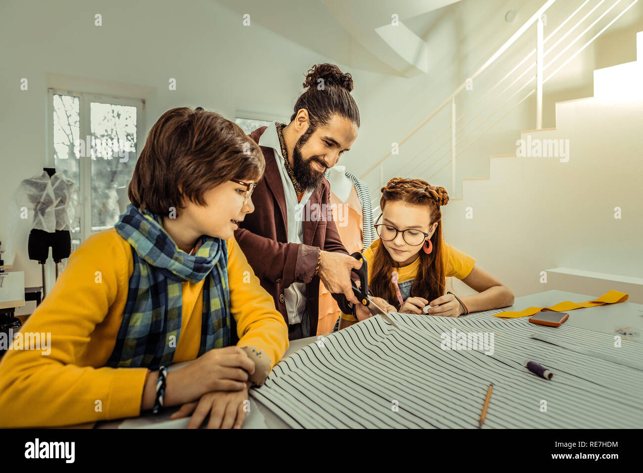 Dark-haired son wearing yellow sweater and scarf looking at father Stock Photo