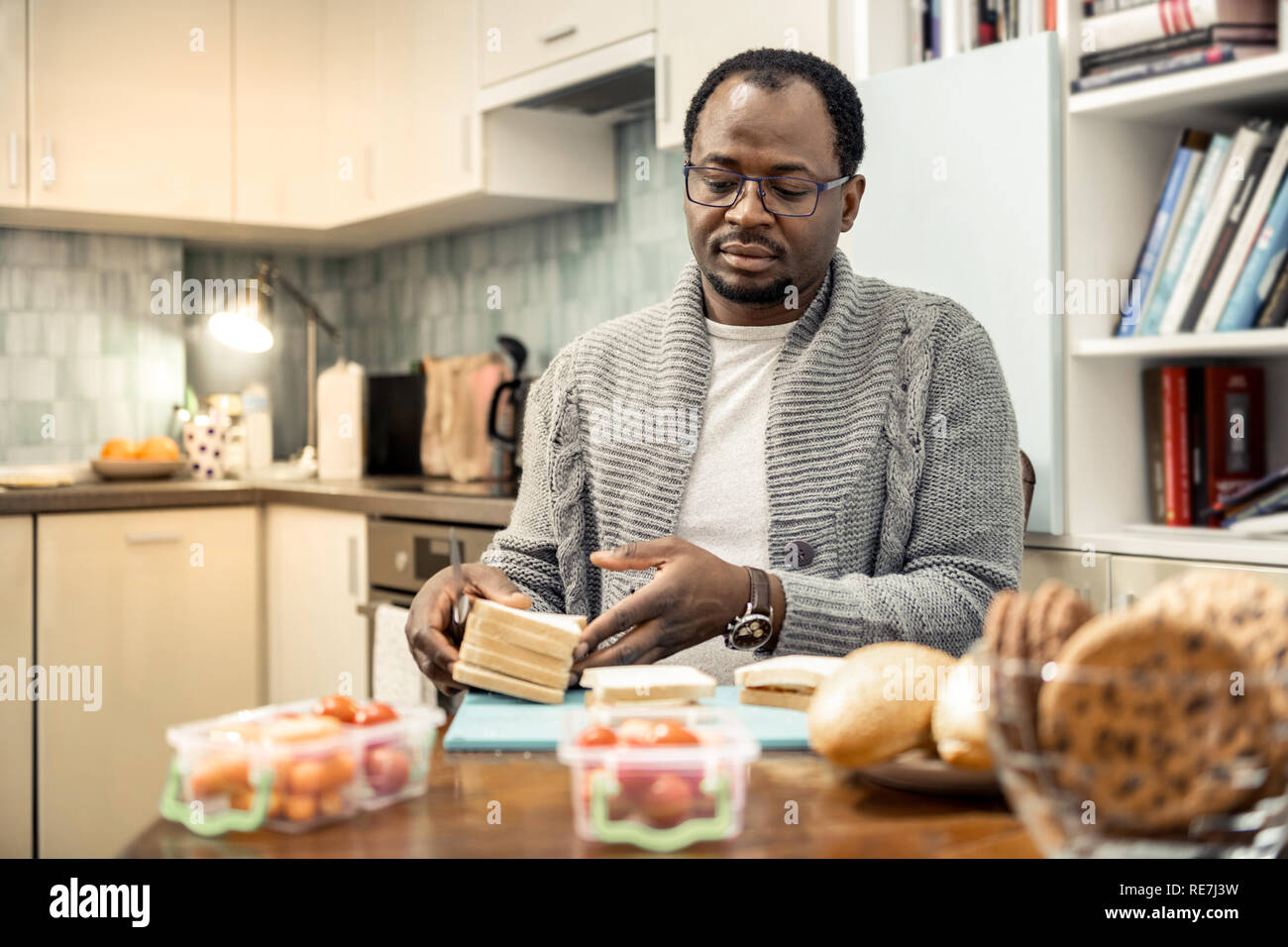 Caring father wearing glasses cooking sandwiches for family trip Stock Photo