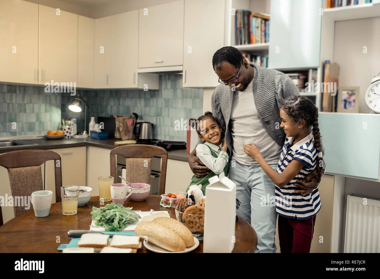 Cute twins feeling lovely while meeting father in the kitchen Stock Photo