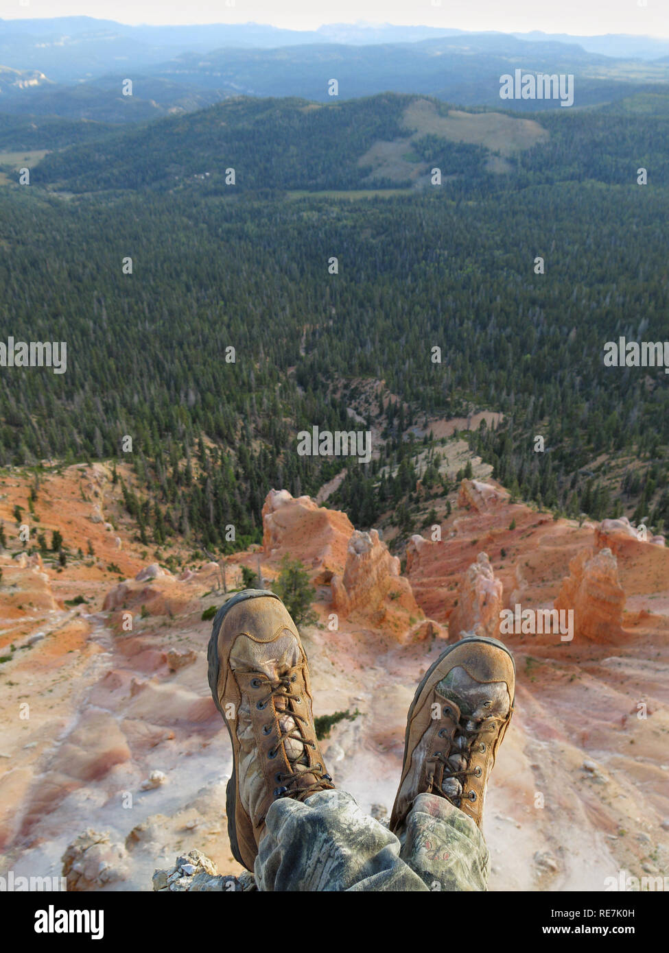 hiker resting on cliff edge overlooking scenic mountains showing boots and feet only Stock Photo