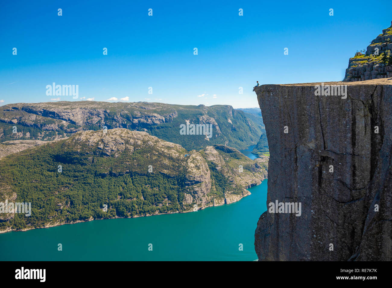 Hiker standing on Preikestolen and looking on the fjerd, Preikestolen - famous cliff at the Norwegian mountains Stock Photo