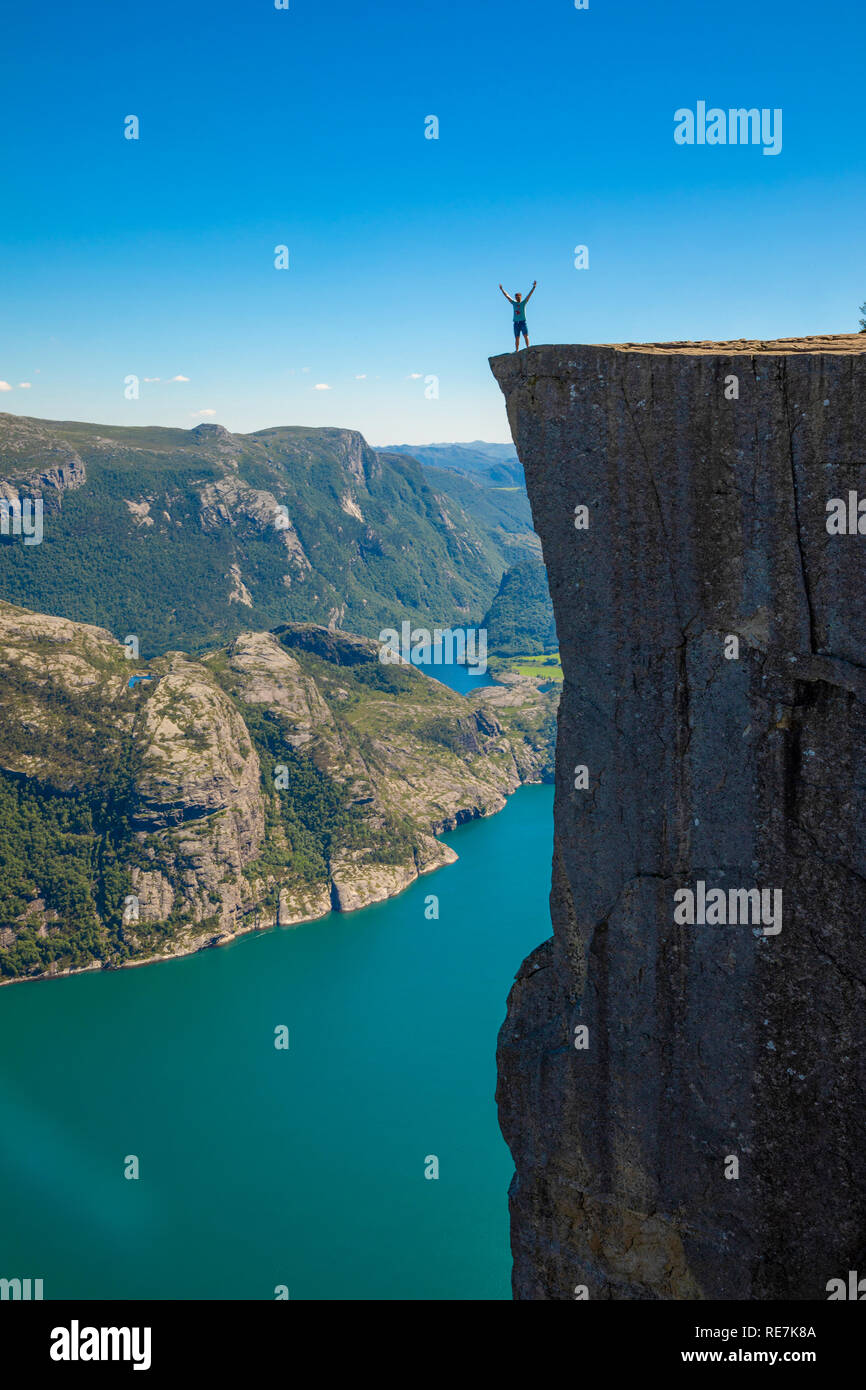 Hiker standing on Preikestolen and looking on the fjerd, Preikestolen - famous cliff at the Norwegian mountains Stock Photo