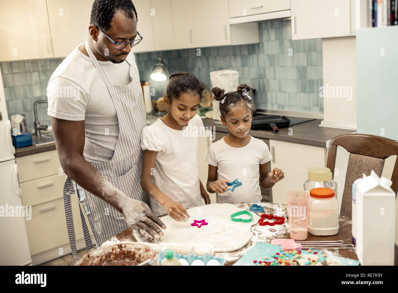 Two daughters feeling amazing while making cookies with father Stock ...