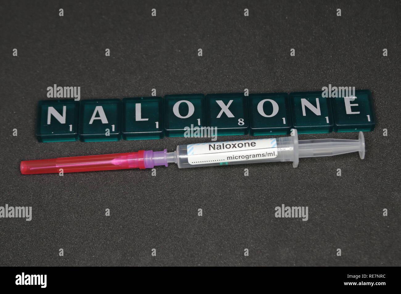 A 2ml Syringe labelled Naloxone and filter / drawing up needle with a word game tiles spelling out Naloxone. Stock Photo