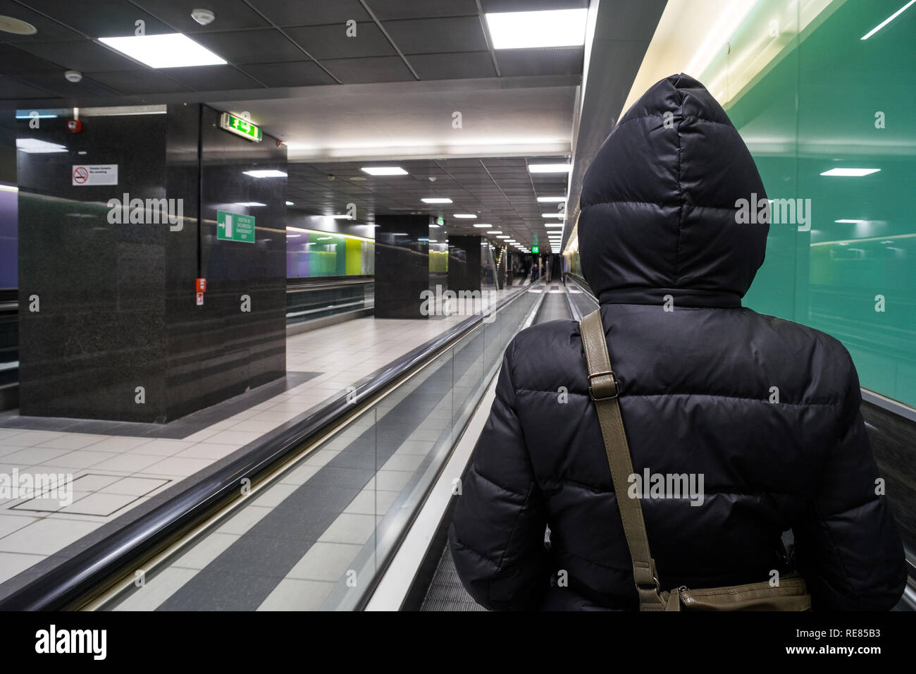 Rome, italy, 12/15/2018: a hooded back woman on a tapis roulant inside the Rome Termini train station tunnel Stock Photo