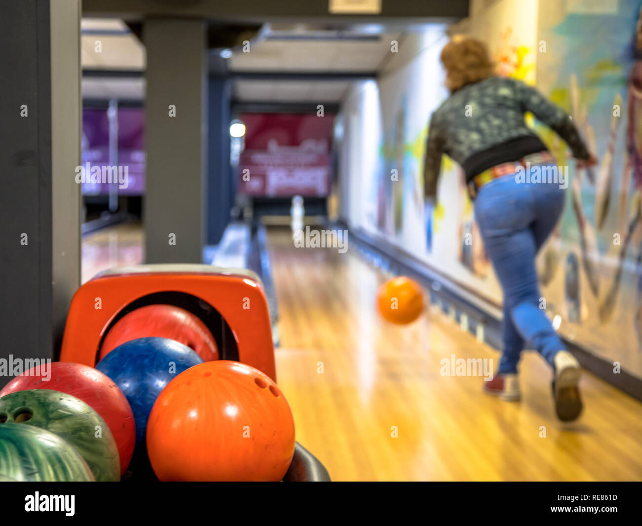 Female bowler throwing bowling ball on indoor bowling alley Stock Photo